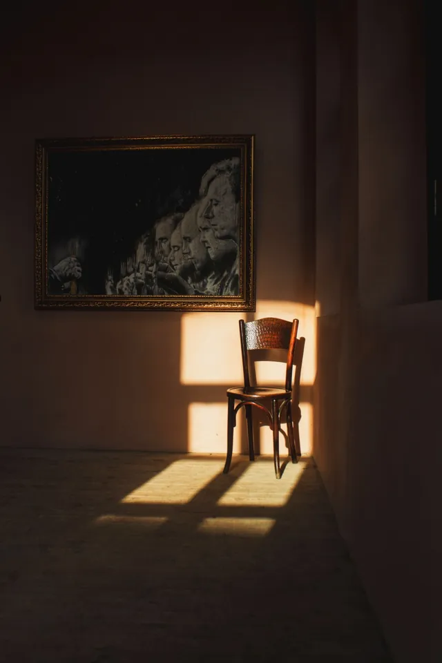 Una silla de madera sola en un rincón, iluminada por la luz de una ventana